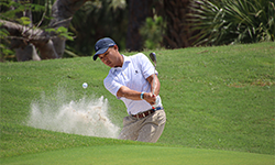 Male golfer hitting shot out of the bunker